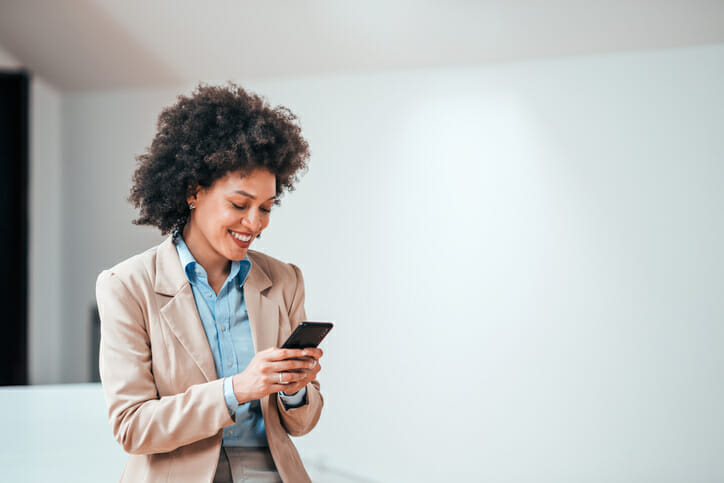 A woman in an office smiles while texting