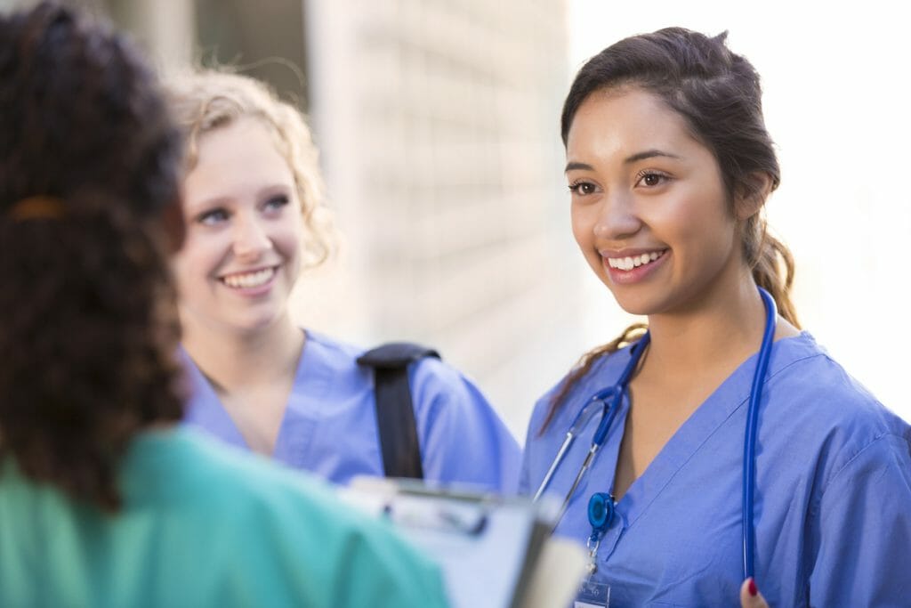Reducing turnover in healthcare: A group of young nurses talk and smile together
