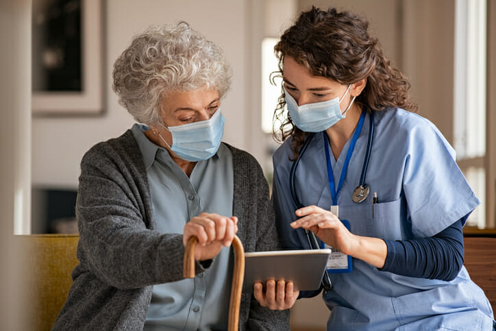 Emerging healthcare technology. A healthcare worker and an older woman look at a tablet together.