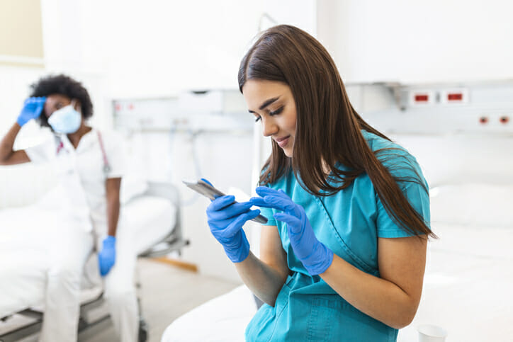 Texting candidates. A young nurse in a hospital looks at her phone