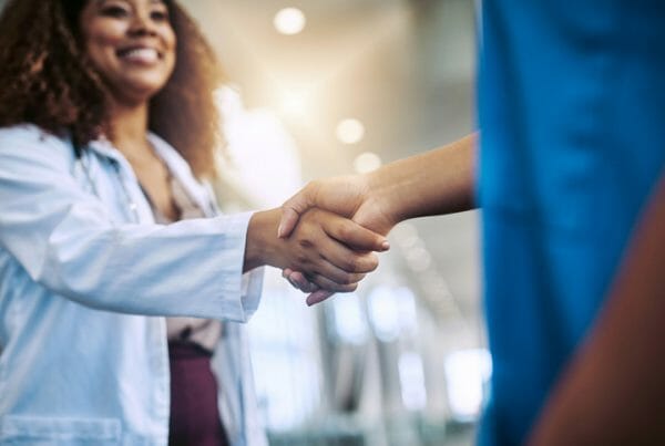 Onboarding checklist. Two medical workers shake hands as a part of healthcare onboarding.